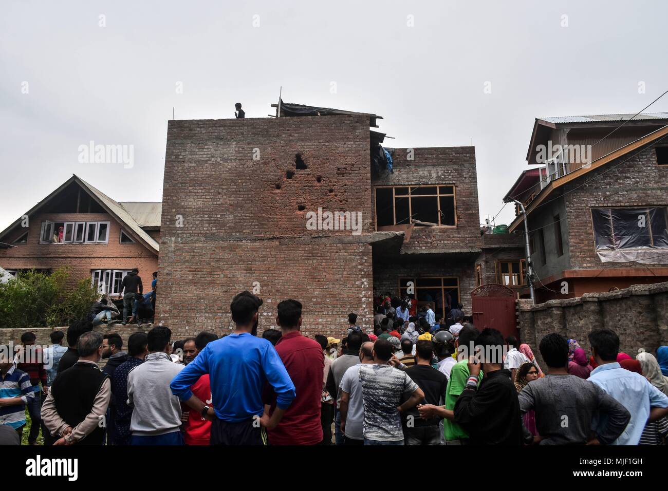 Kashmir, India, 5 May 2018.  Kashmiri residents assemble near the damaged hous militants were trapped during an encounter in Srinagar, Indian administered Kashmir. Three suspected militants and one civilian have been killed while three Indian paramilitary men sustained injuries in a gun battle in Srinagar, the summer capital of Indian administered Kashmir. The encounter started after government forces cordoned off a Chattabal area following the presence of militants in the area, officials said.  the militants were believed Credit: ZUMA Press, Inc./Alamy Live News Stock Photo