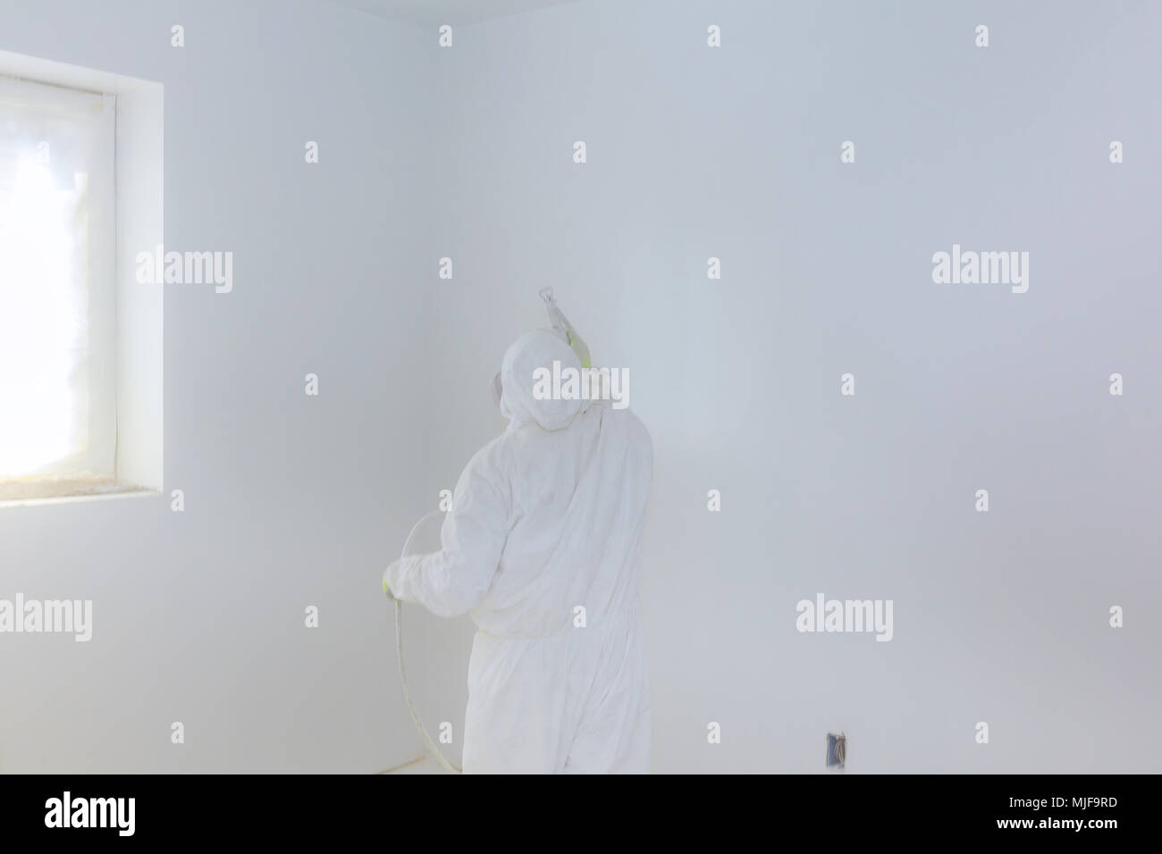 Worker Painting Wall With Airless Spray Gun In White Color Stock