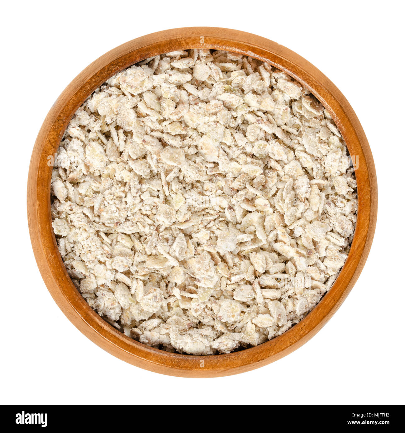 Buckwheat flakes in wooden bowl. Rolled coarse wholegrain cereal. Wheat and gluten free. Edible and raw food. Fagopyrum esculentum. Stock Photo