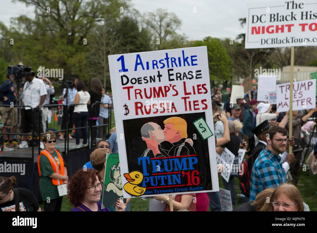 Protesters hold protest signs during the Tax March, an effort to encourage President Donald Trump to release his taxes in Washington, D.C. on April 15th, 2017. Stock Photo