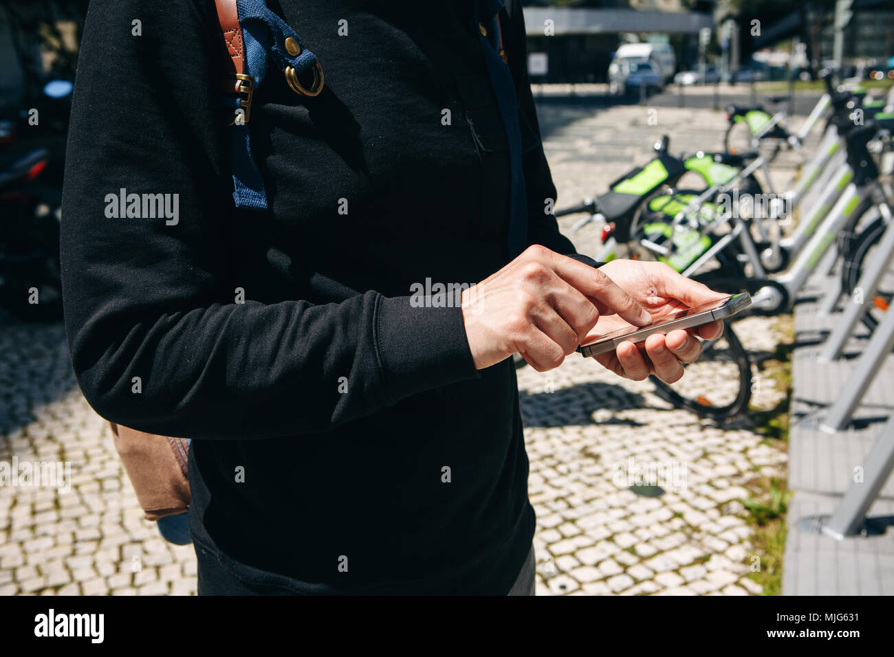 Man or tourist rents bicycle or city alternative ecological transport using the mobile app on your phone. Or he simply dials a number and calls or use Stock Photo