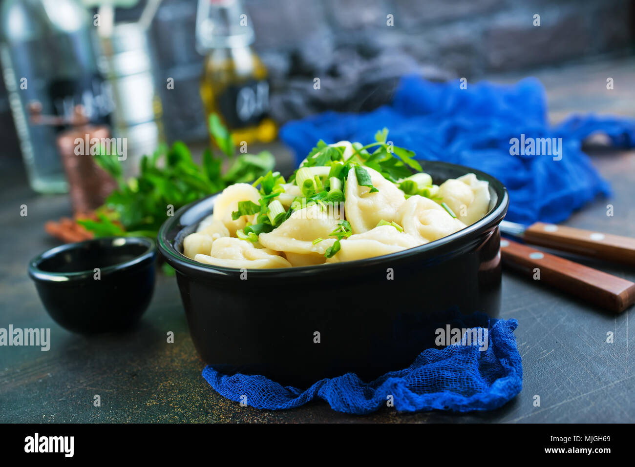 pelmeni in bowl, boiled pelmeni with fresh greens and sult Stock Photo