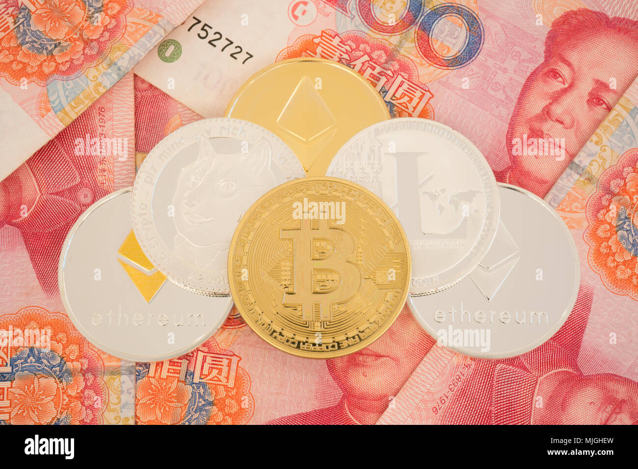 Real cryptocurrency coins on chinese yuan bills - crypto currency in china concept Stock Photo