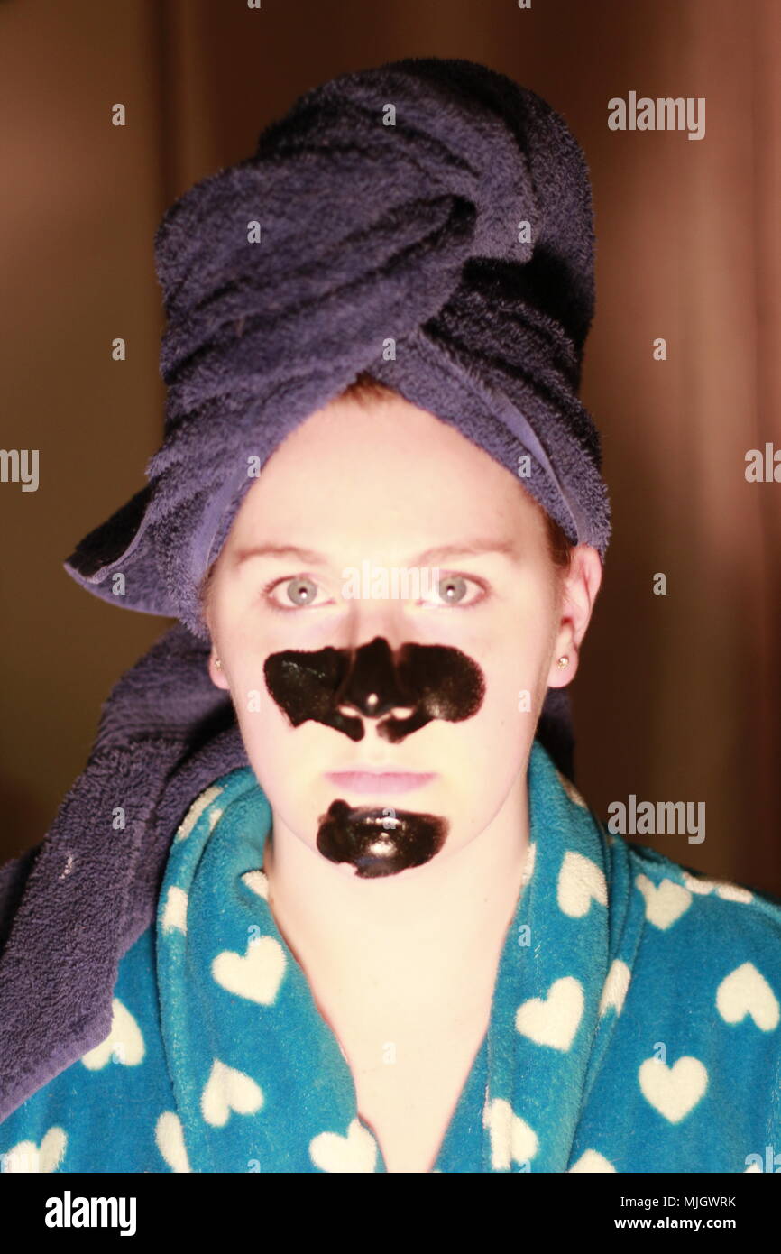 Women with a charcoal mask on as part of her beauty regime. This is a caucasian women who is aged 20 to 25 years old and is of British descent. Stock Photo