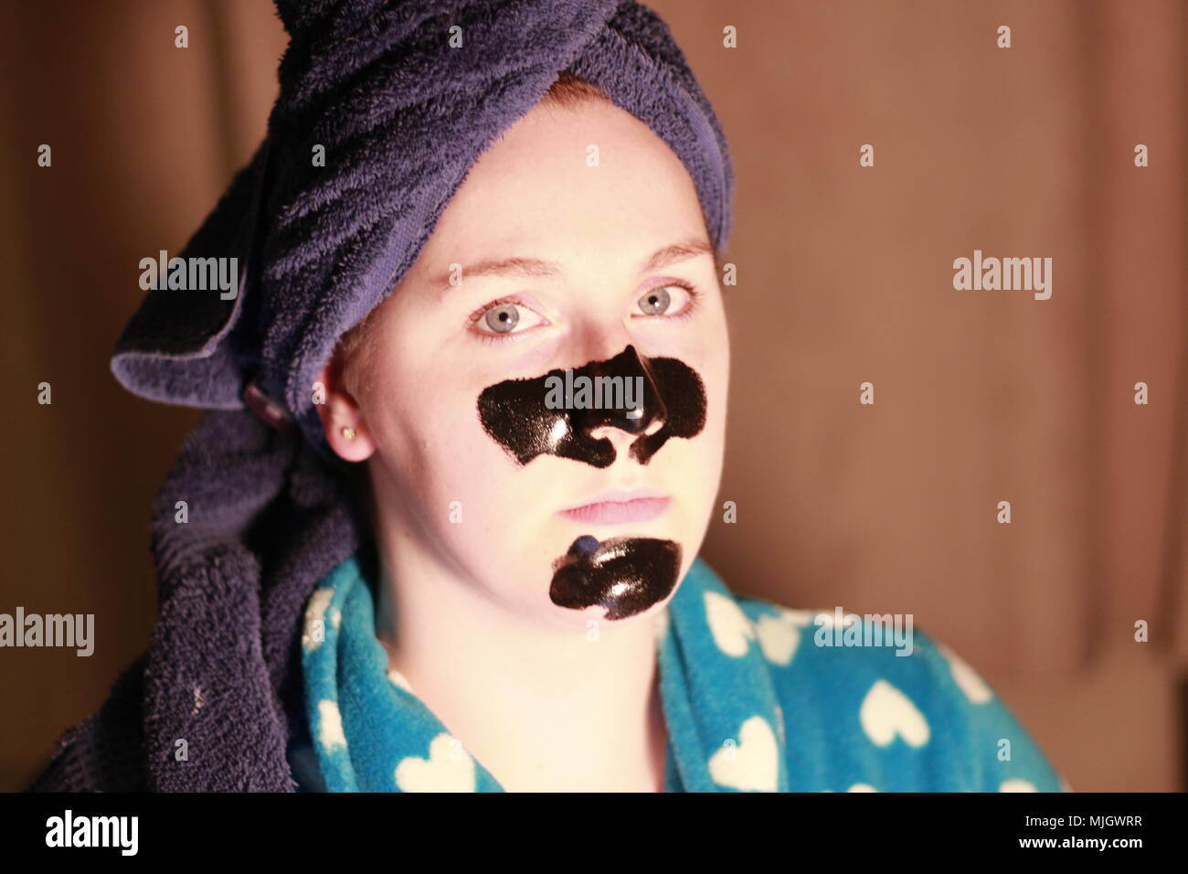 Women with a charcoal mask on as part of her beauty regime. This is a caucasian women who is aged 20 to 25 years old and is of British descent. Stock Photo