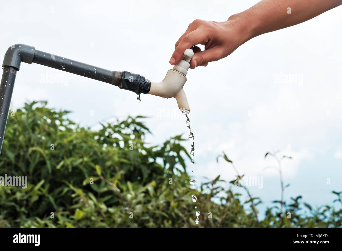 Caucasian woman hand closing water tap in the garden. Wasting of water resource Stock Photo