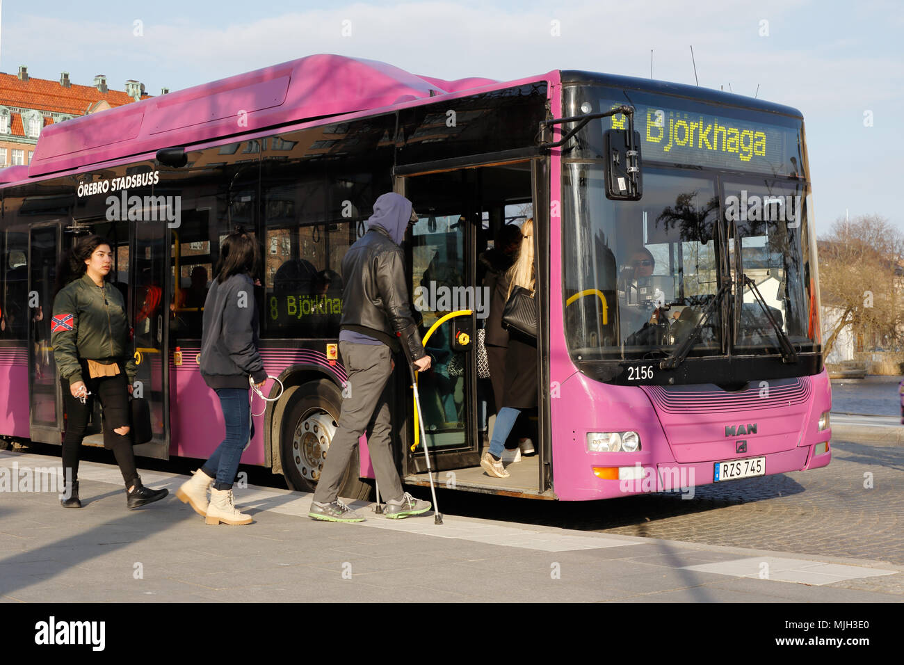 Orebro, Sweden - April 4, 2017:: Passengers boarding a violet city bus at the stop Jarntorget. Stock Photo