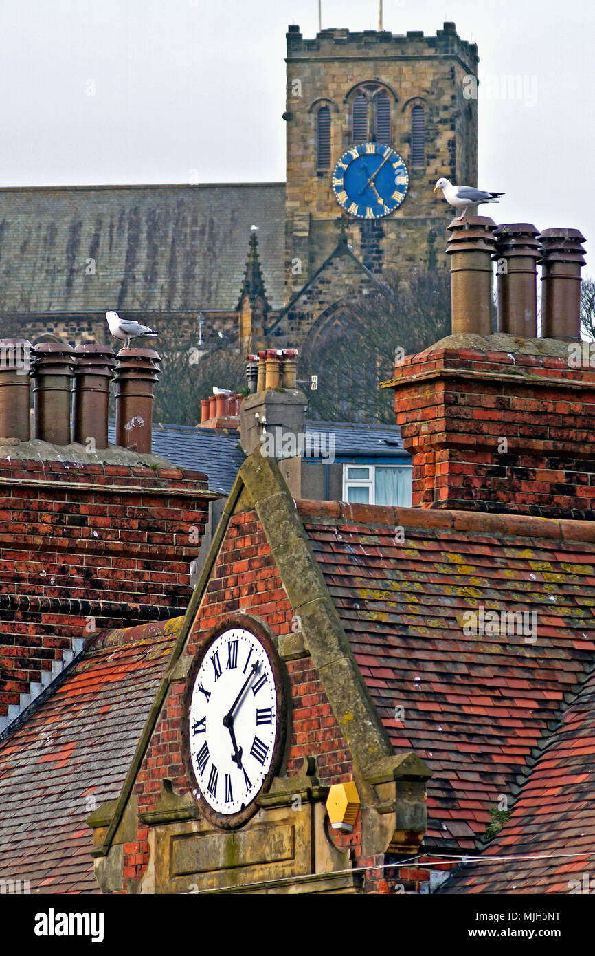 Just Gone Five! Scarborough’s St Mary’s Church and the town’s West Pier buildings’ clocks tell 2 seagulls what time it is. Stock Photo