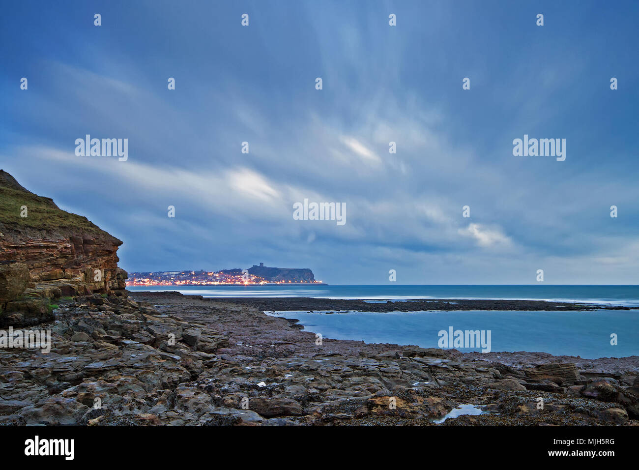 South Bay streetlights illuminate the seafront of Scarborough’s headland under swirling clouds in pre-dawn light. Stock Photo
