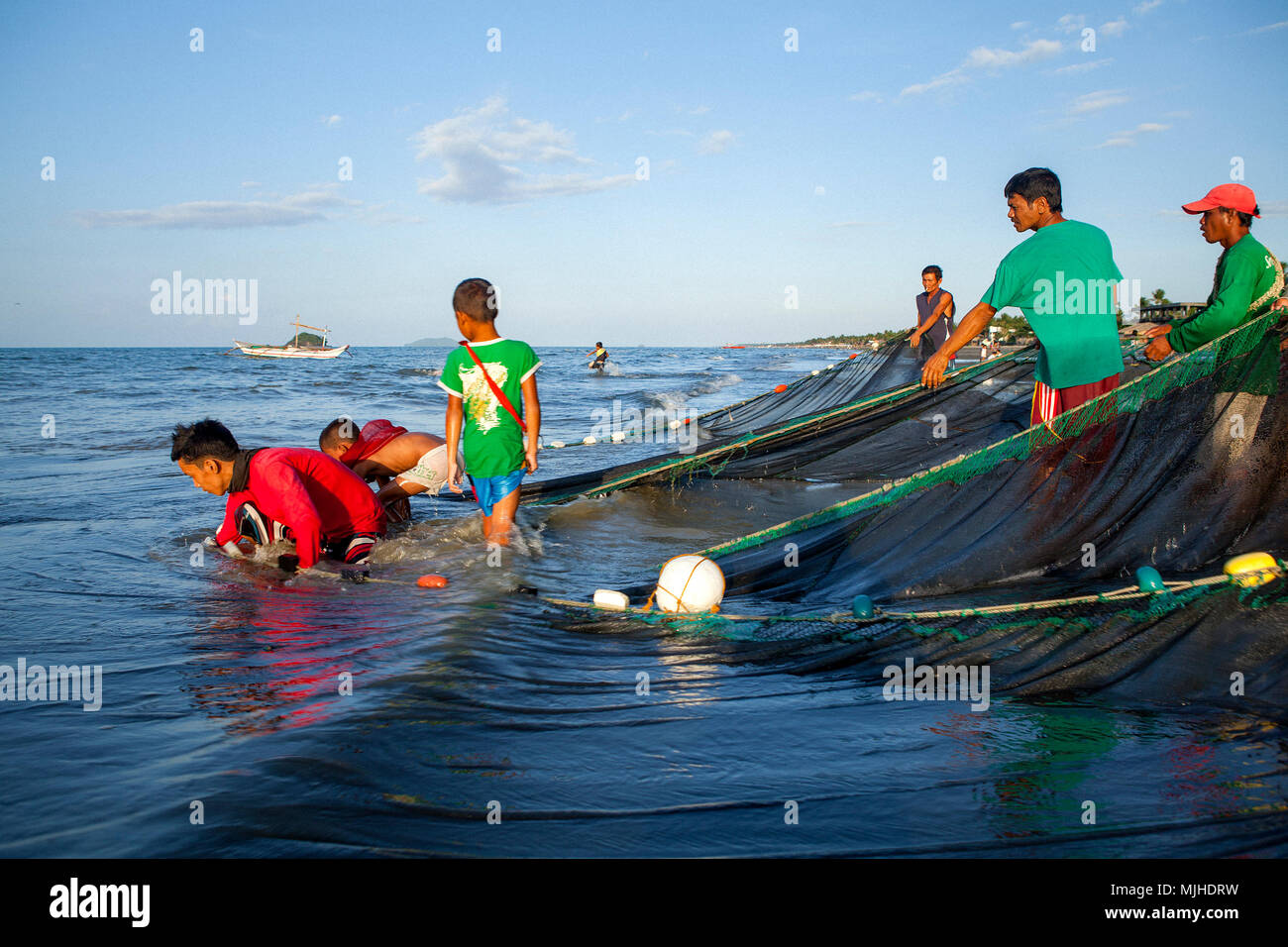 A group of Filipino fishermen haul their seine fishing net to shore at  BayBay Beach in Roxas City, Panay Island, Philippines Stock Photo - Alamy