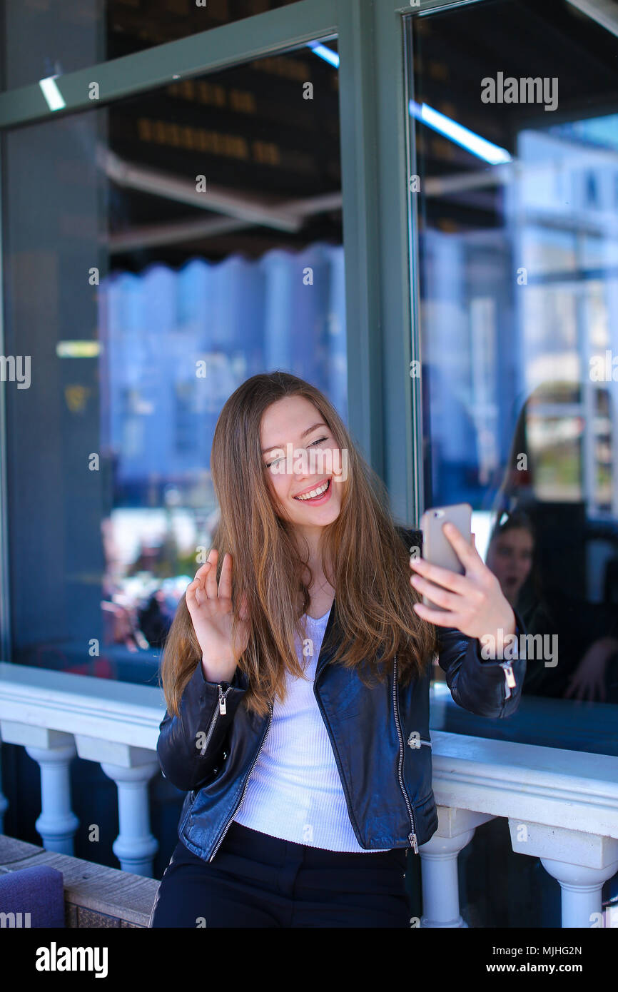 Cute female person making video call by smartphone at cafe. Stock Photo