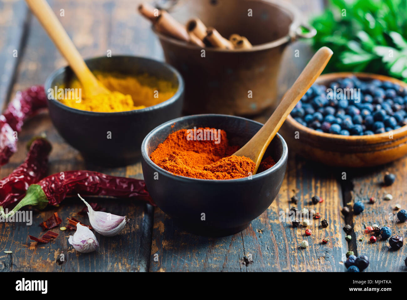 Small bowls filled with spices on rustic wood table. Various