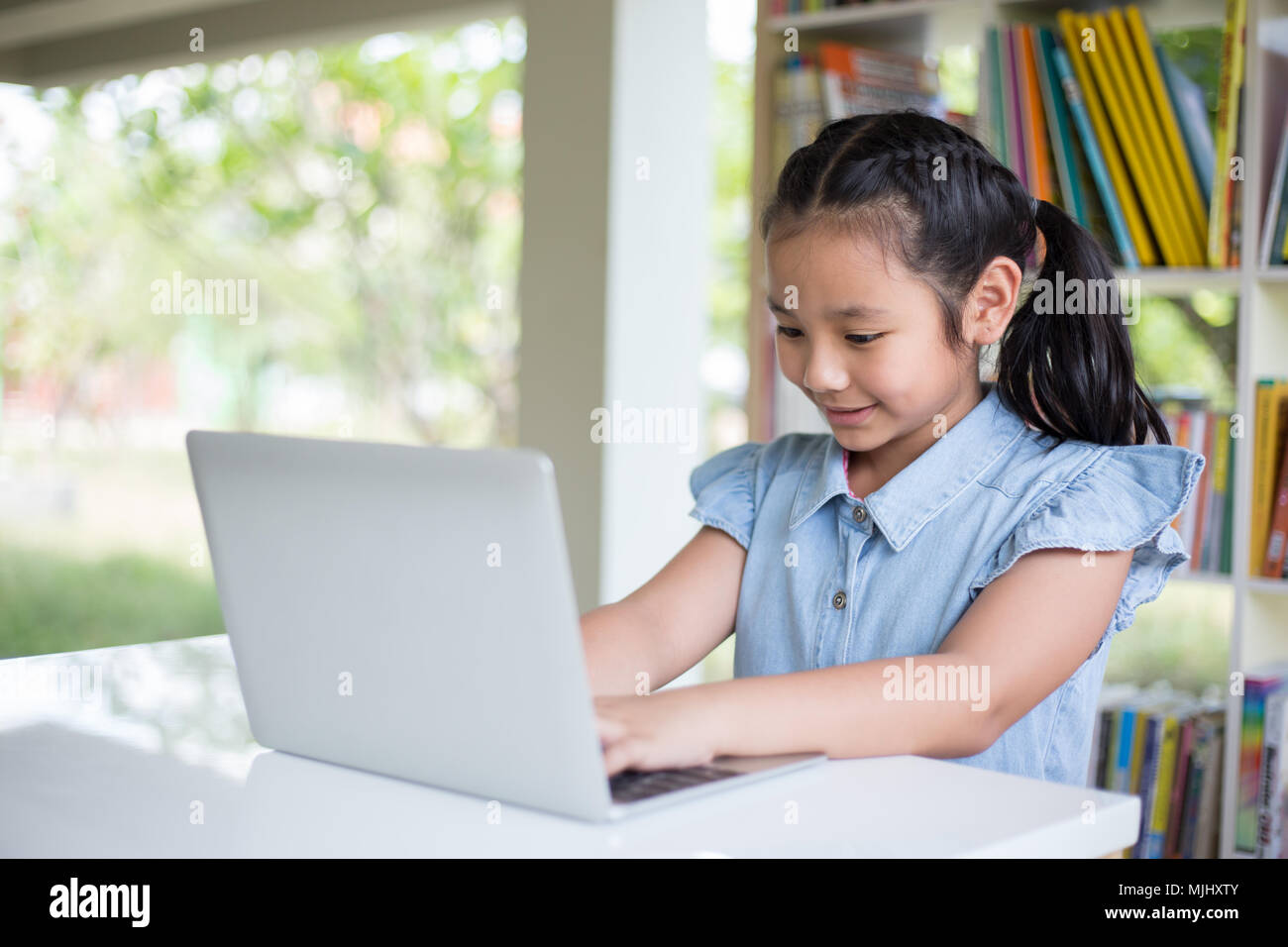 Young girl using computer at elementary school. Happy female child ...
