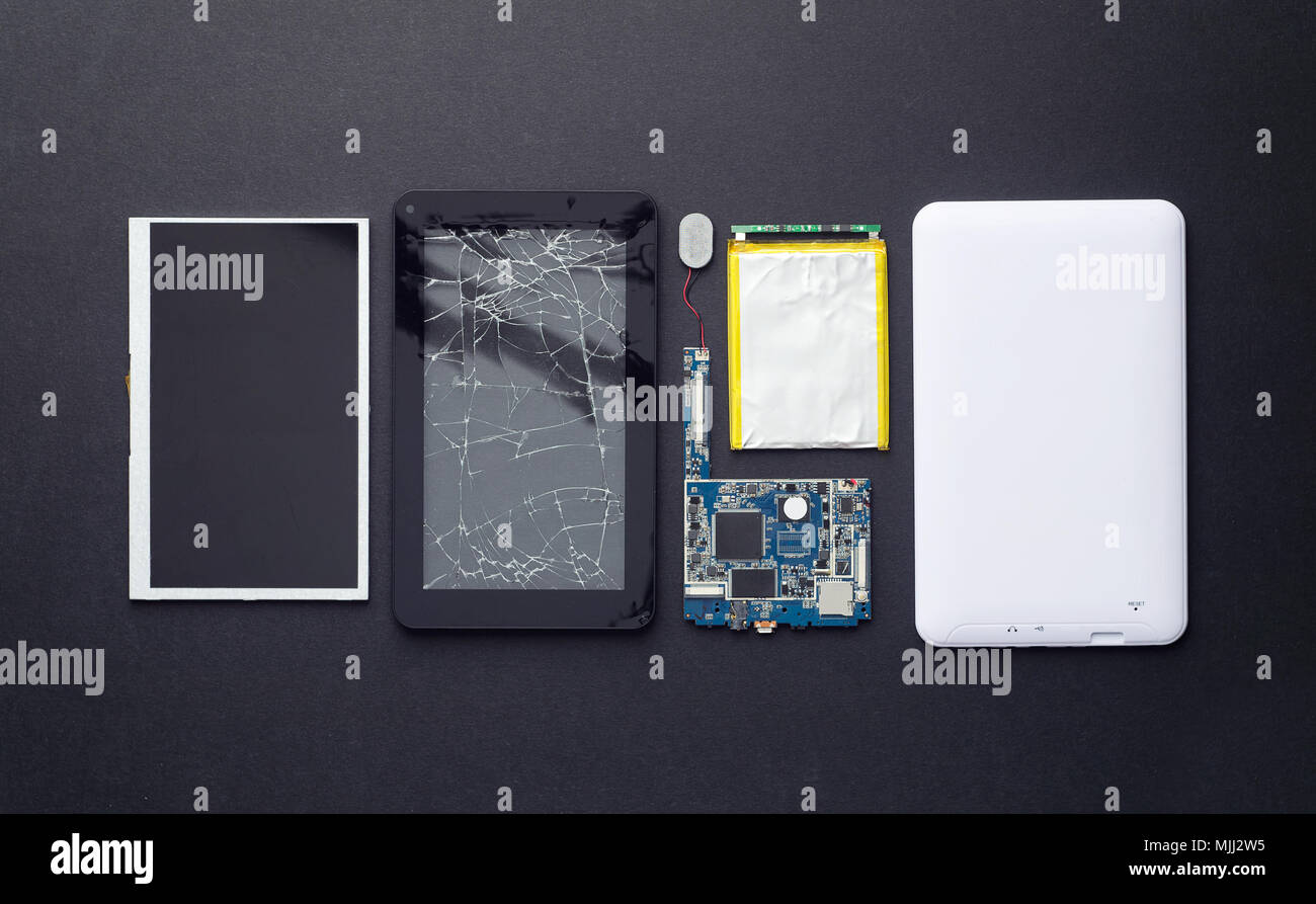 Components of a broken tablet organized over black background, top view Stock Photo