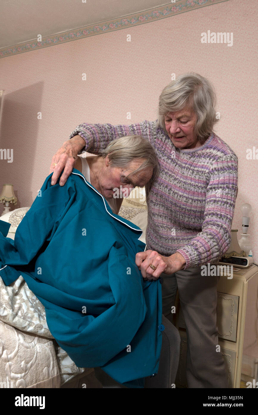 Elderly woman helping her brother get undressed for bed Stock Photo - Alamy