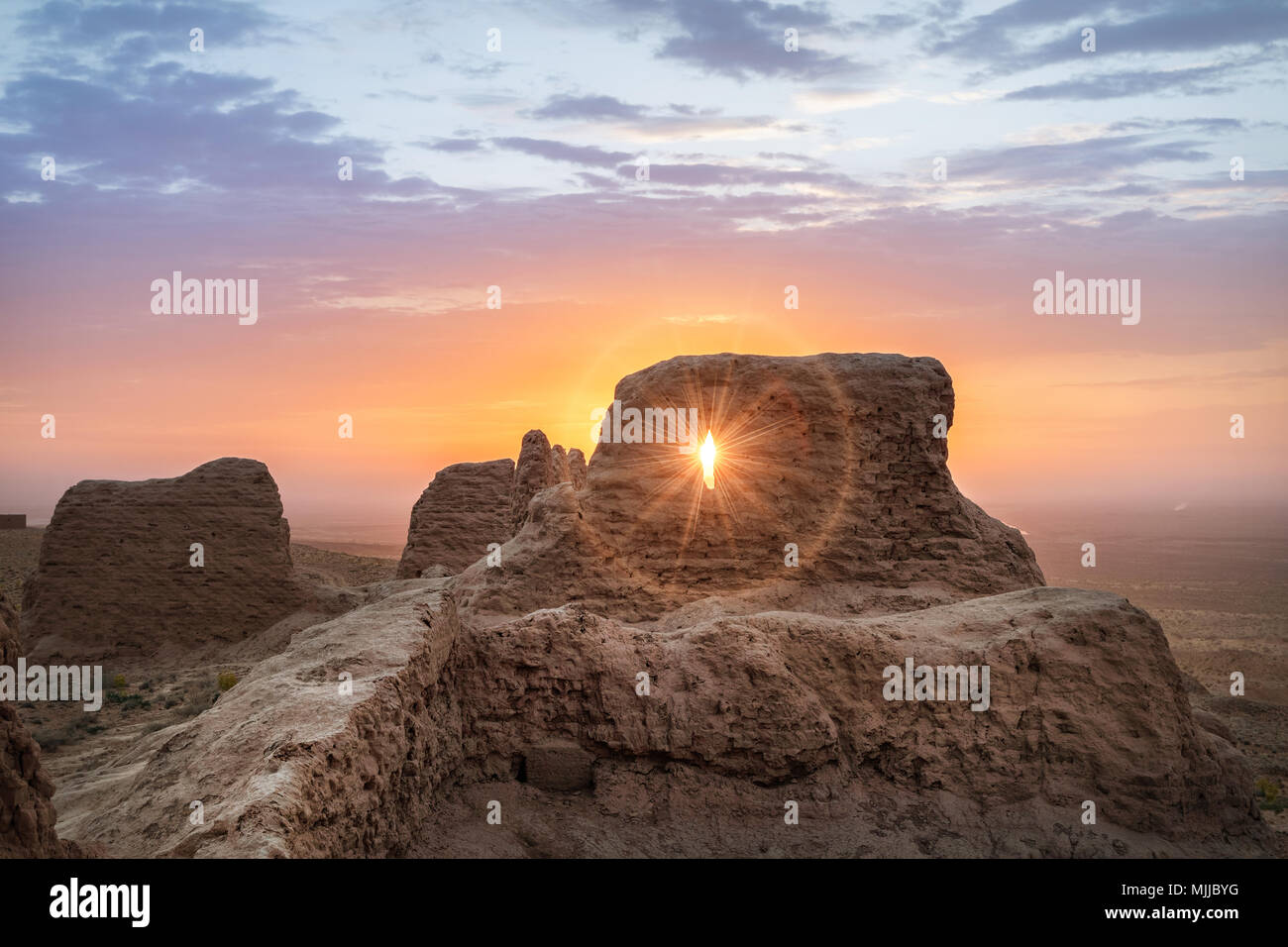 Rays of rising sun permeate through ruins of ancient Ayaz Kala fortress in Kyzylkum desert, Uzbekistan Stock Photo