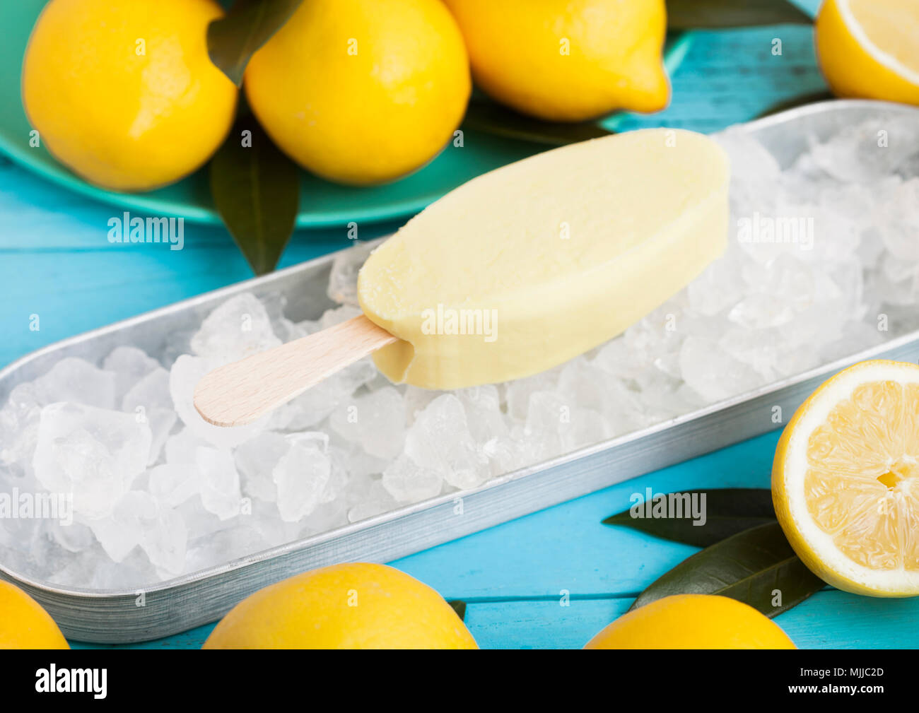 Ice cream made from lemon frozen juice sherbet in still tray and raw lemons on blue background Stock Photo