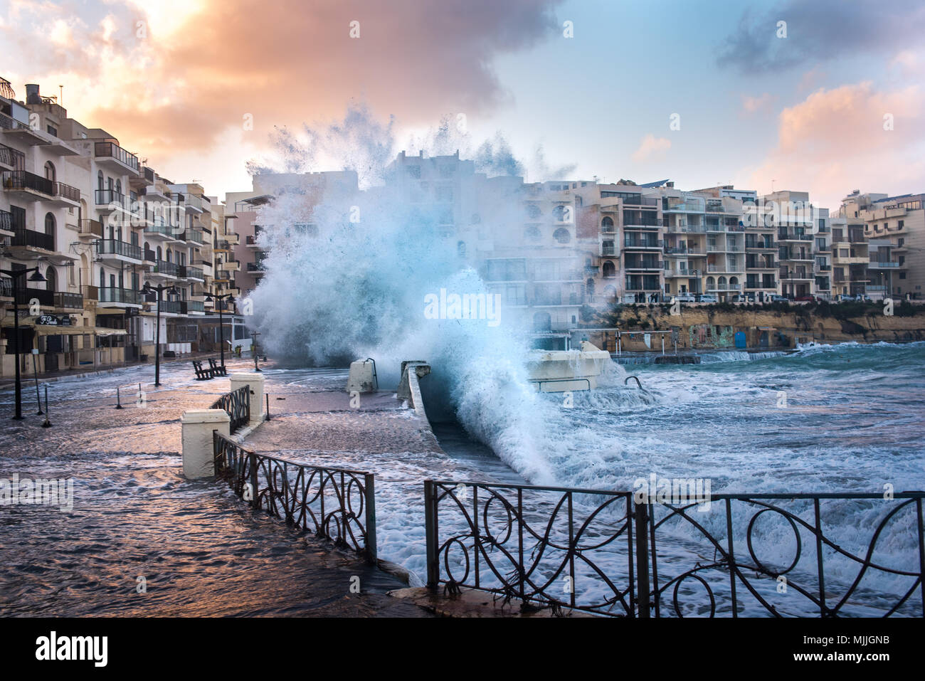 Marsalforn, Malta - January 2, 2018: Big waves are crashing into the Marsalforn promenade. The village of Marsalforn is on the north caost of Gozo, which is an island of the Maltese archipelago and the second-largest island of Malta. Stock Photo