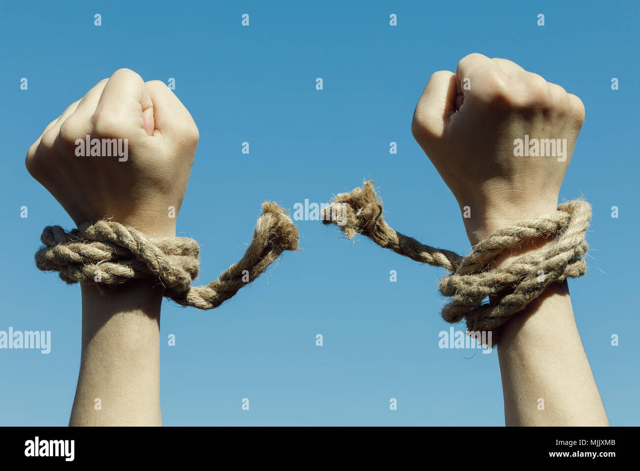 Hands tearing shackles the background of blue sky. Concept of freedom Stock Photo