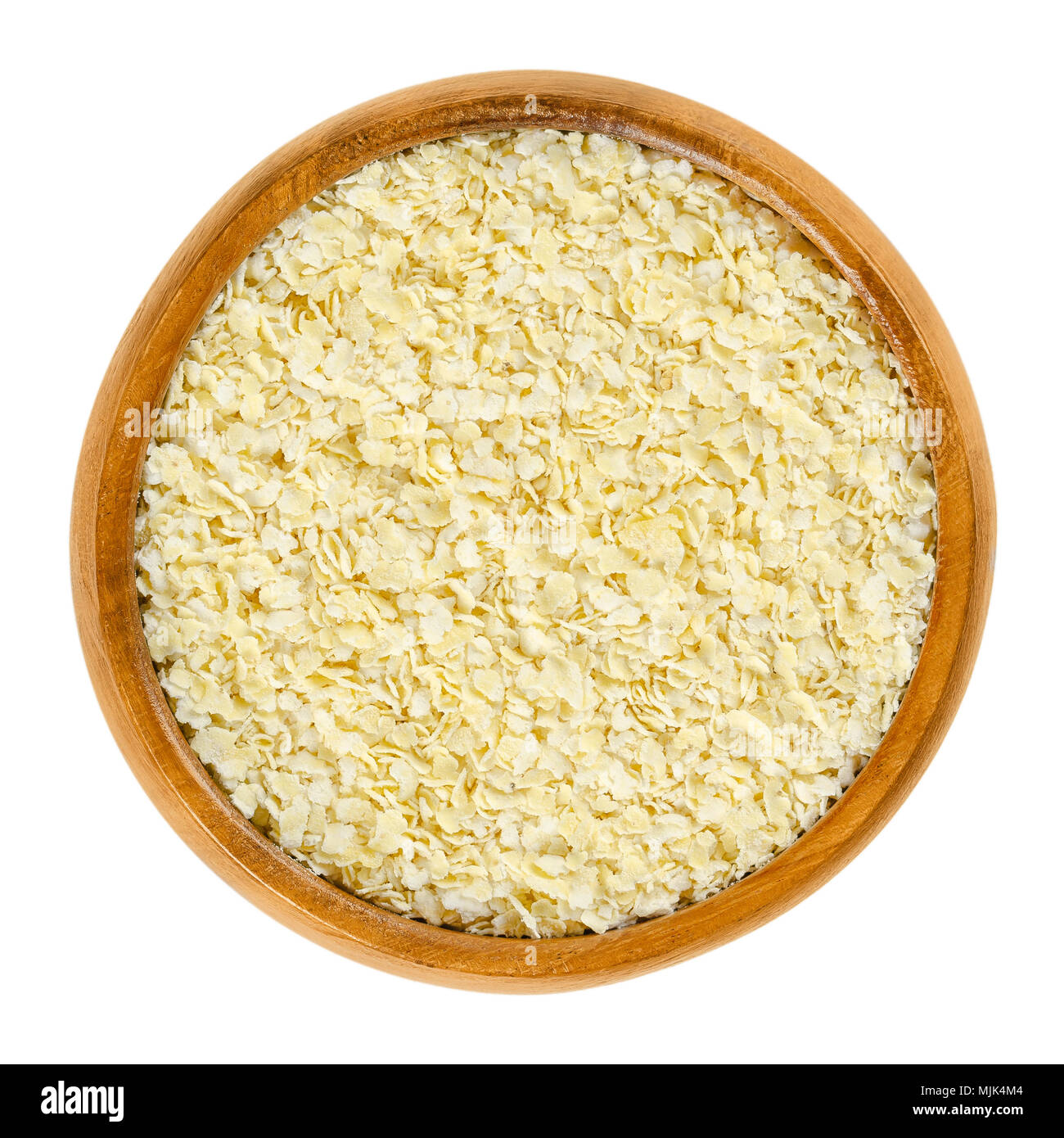 Millet flakes in wooden bowl. Light, yellow rolled millet, used for porridge, muesli and baking. Wheat and gluten free grain. Isolated macro photo. Stock Photo
