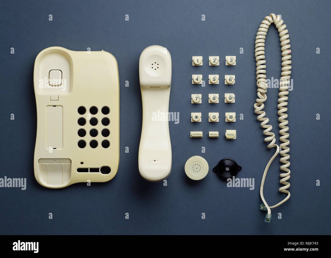 Parts of vintage home telephone well organized over dark blue
