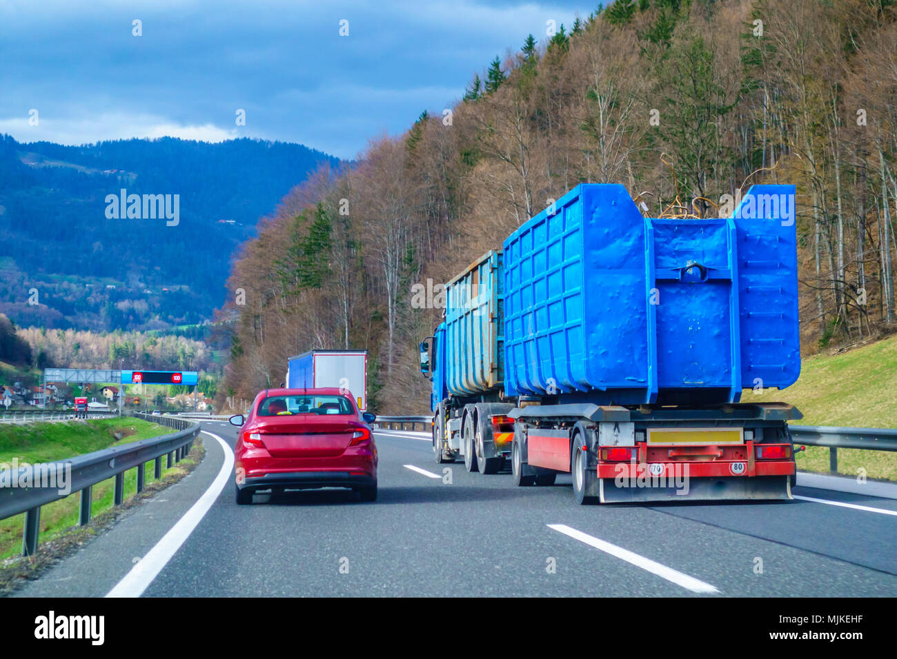 Red car overtaking blue truck on highway Stock Photo