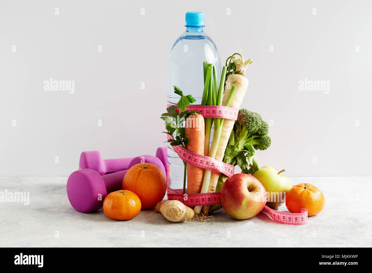 Bottle of water with a pink measuring tape, vegetables and fruit. Concept health, diet and nutrition. Stock Photo