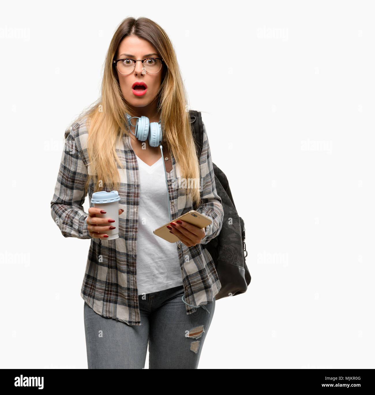 Young student woman with headphones and backpack scared in shock ...