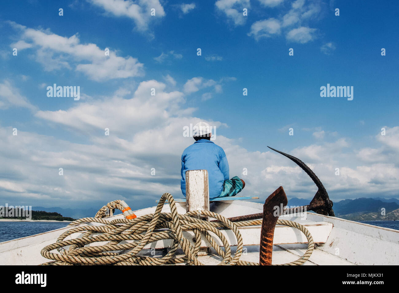 fisherman sit on nose of fishing boat with anchor and rope Stock Photo