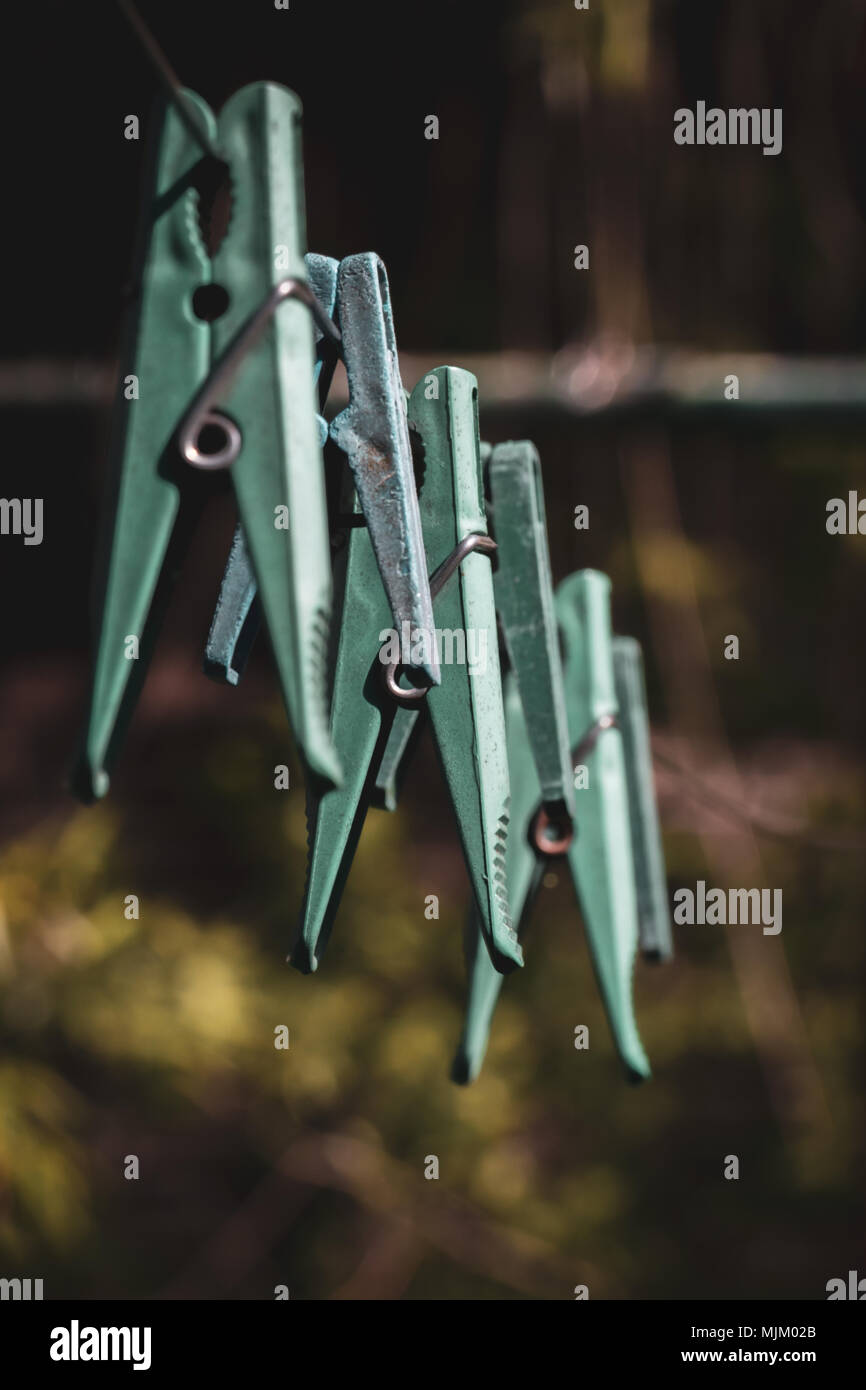 Old plastic clothespins on a rope hanging outside house, toned green, vintage look Stock Photo