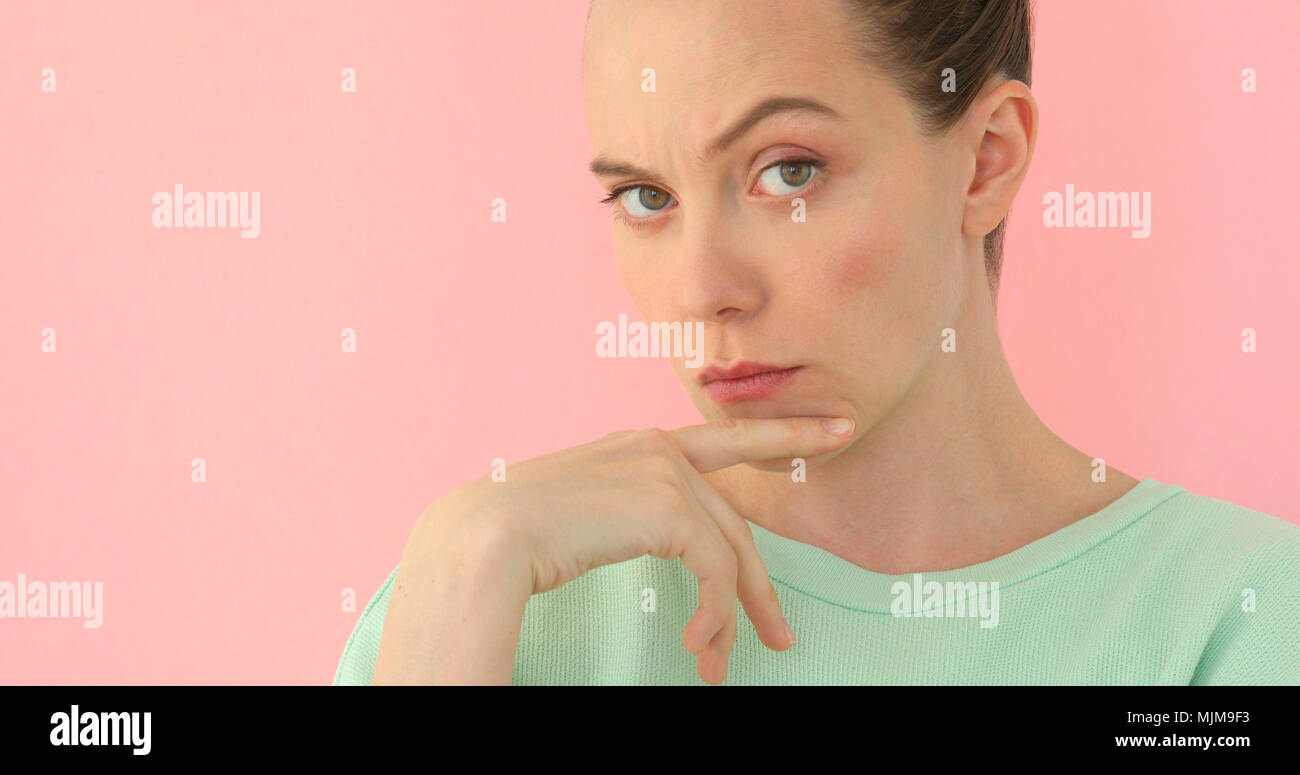 Pretty girl shows indignation pink background Stock Photo