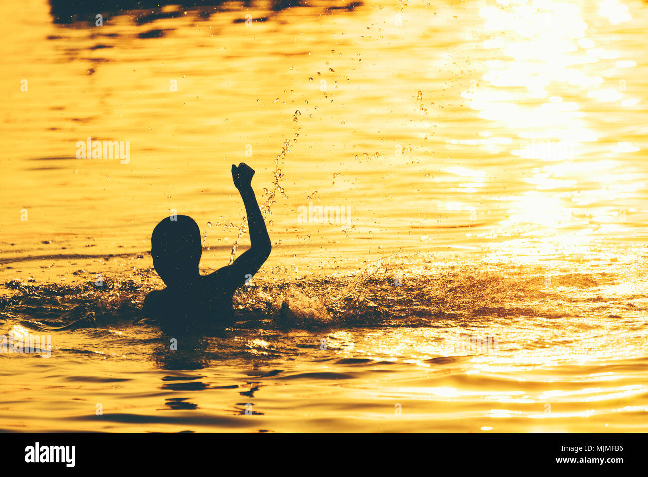 The boys are playing the water in the sunset Stock Photo - Alamy