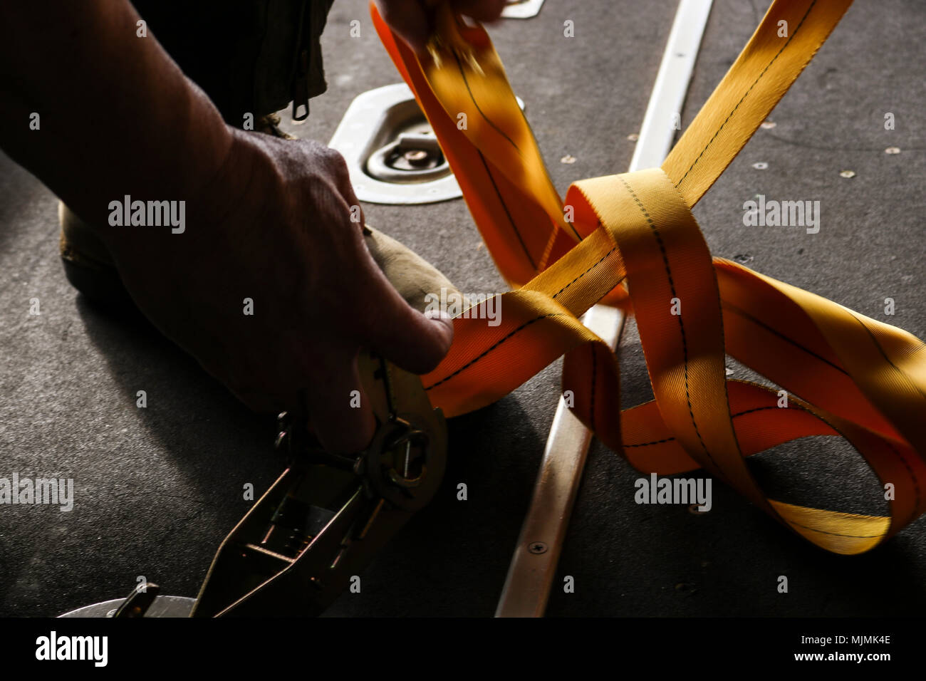 Royal Australian Air Force Flight Sgt. Tim Broughill, 37th Squadron loadmaster, tightens straps to secure a bundle inside of a RAAF C-130J Super Hercules at Andersen Air Force Base, Guam, Dec. 10, 2017. OCD volunteers built 120 bundles to provide about 20,000 islanders with food, educational material and other supplies. (U.S. Air Force photo by Staff Sgt. David Owsianka) Stock Photo