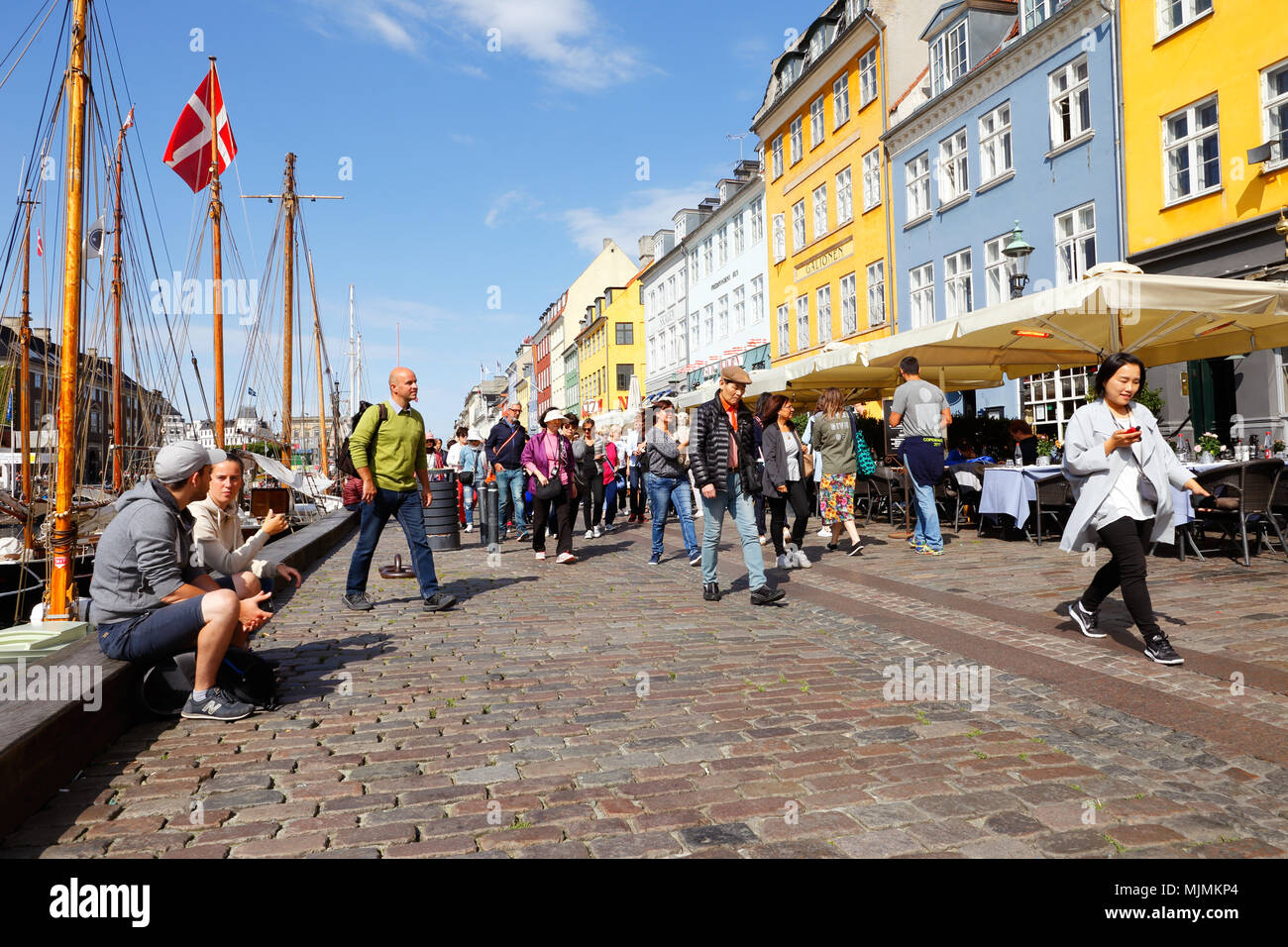 Copenhagen, Denmark - August 24, 2017: People valking the street in Nyhavn there restaurants with outdoor seating are located. Stock Photo