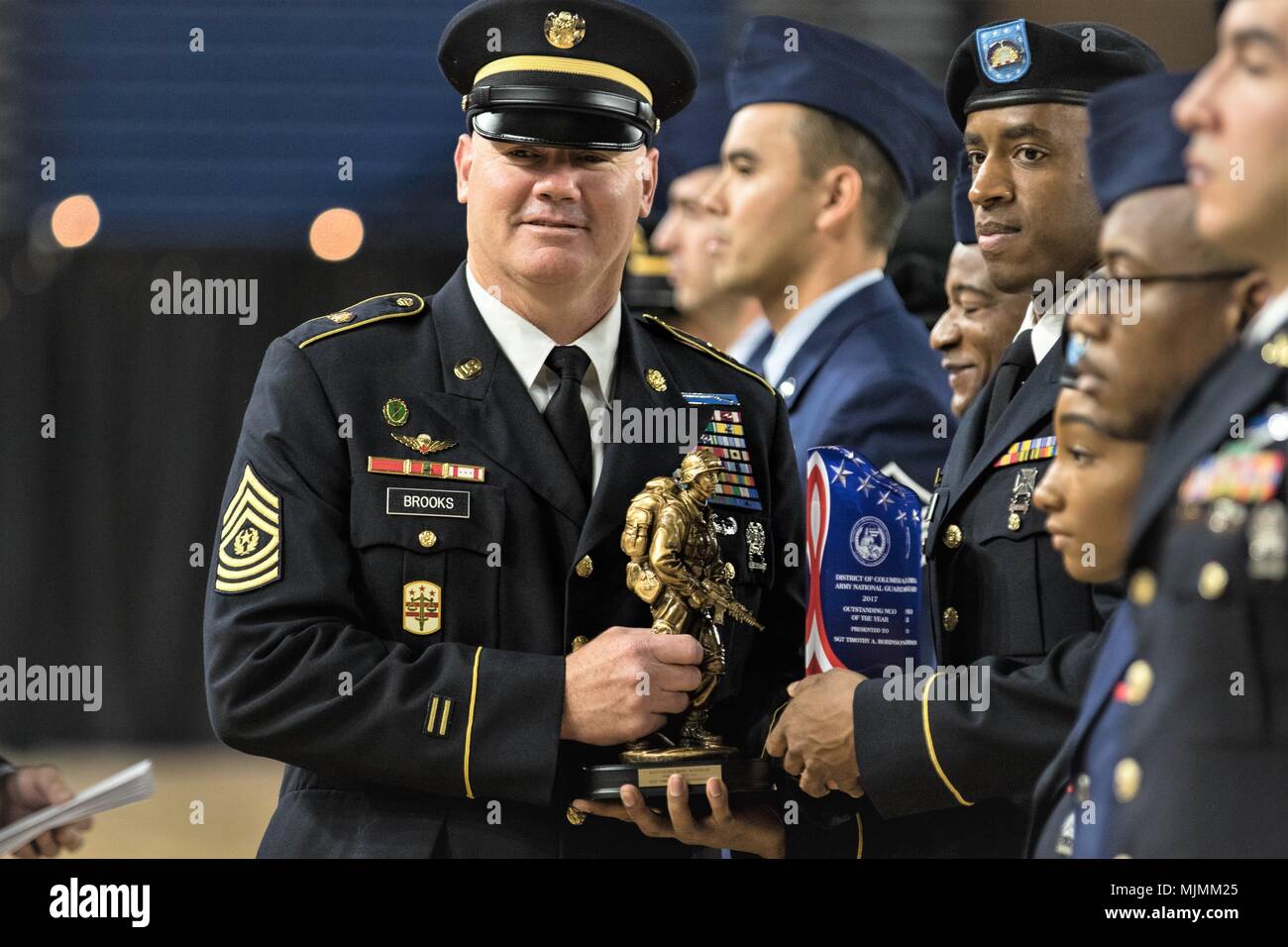 Command Sgt. Maj. Michael F. Brooks prepares to hand a trophy to Sgt. Timothy A. Robinson, the recipient of the 2017 District of Columbia National Guard Best Warrior (Army) award, at the annual Awards and Decorations Ceremony on December 3, 2017 at the DCNG Armory, Washington, D.C.. Brooks assumed responsibility for the DCNG as Senior Enlisted Leader, and will serve as the principal advisor of enlisted matters to the Acting Commanding General of the DCNG. (Photo by Sgt. Tyrone Williams/Released) Stock Photo