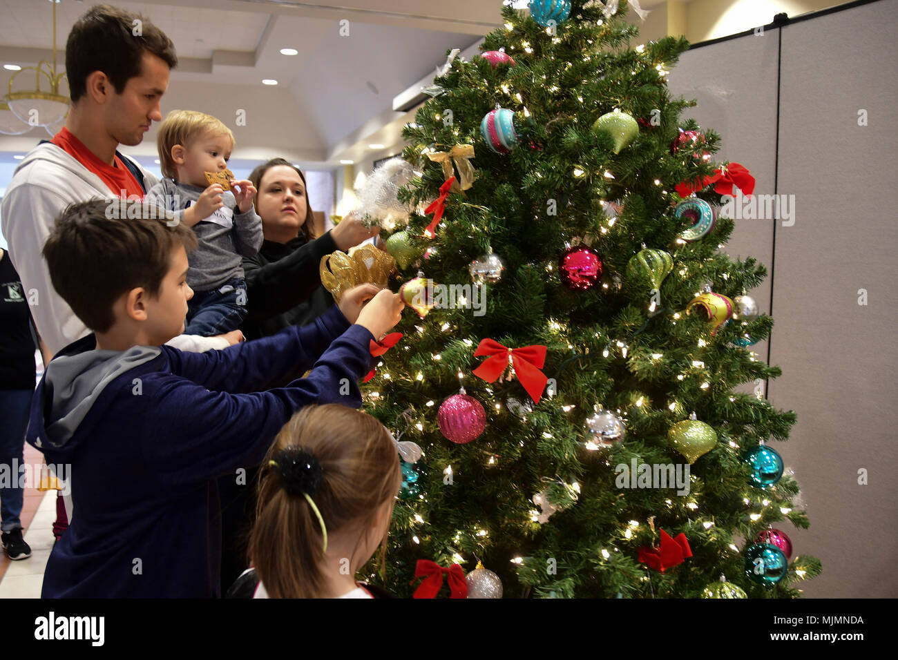 Family members place silver ribbons on the Christmas tree in honor of