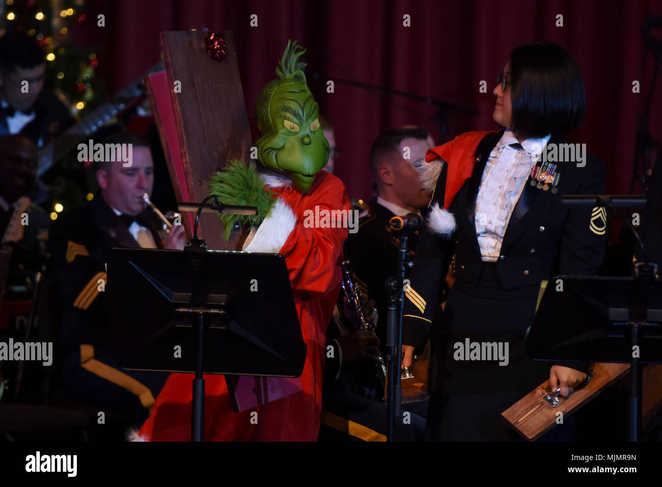 U.S. Army Sgt. 1st Class Grace Chin, U.S. Army Training and Doctrine Command Band percussionist, performs a sandpaper ballet with special guest, the Grinch, during a holiday concert series at Fort Monroe Theater in Hampton, Va., Dec. 7, 2017. Currently, there are over 100 bands throughout the Army increasing morale, recruiting new Soldiers and promoting the Army’s mission to fight and win the nation’s land dominance war. (U.S. Air Force photo by Senior Airman Kaylee Dubois) Stock Photo