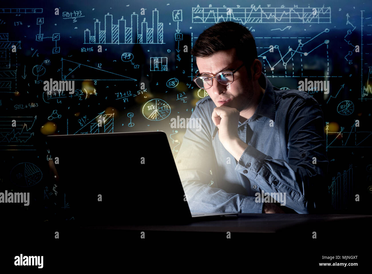Young handsome businessman working late at night in the office with ...
