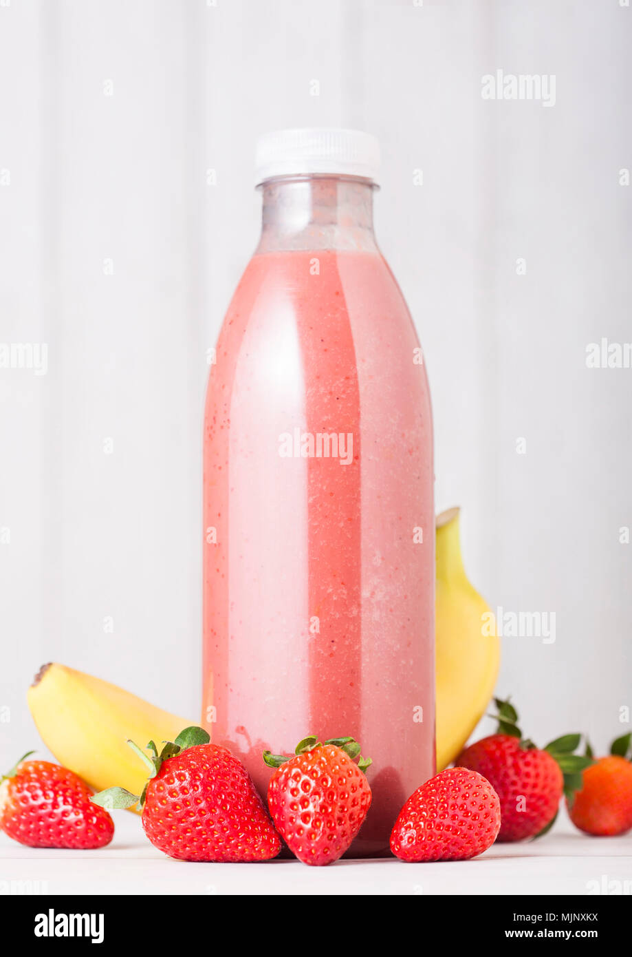 Plastic bottle with fresh summer berries smoothie on wooden background.Strwberry and banana flavour. Stock Photo