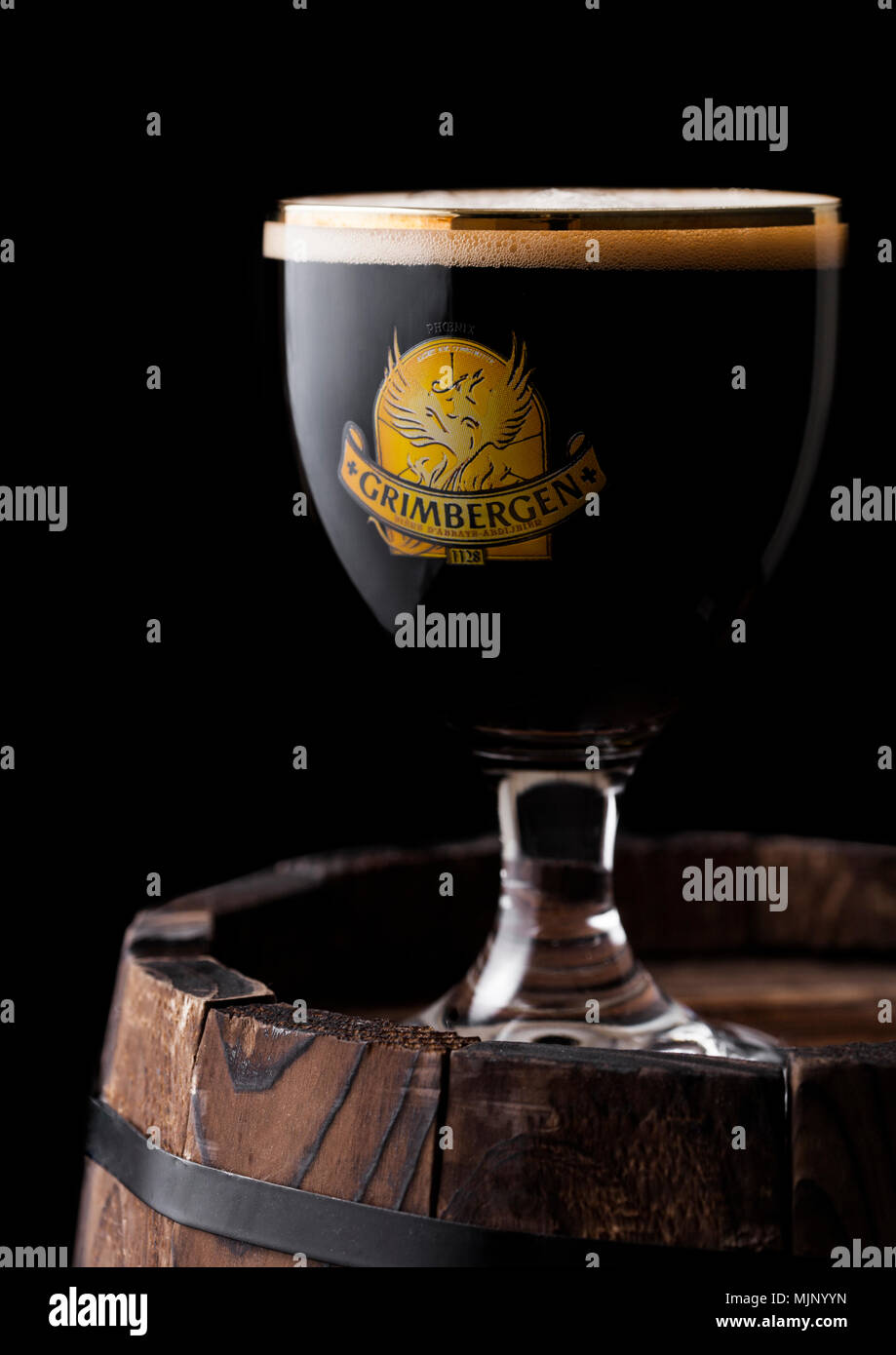 LONDON, UK - MAY 03, 2018: Cold Glass of Grimbergen dubbel beer on wooden barrel and black background. Stock Photo