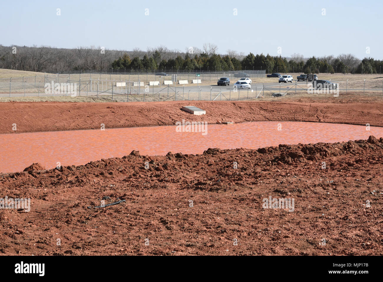 A large water retention pond has been created to capture run-off near the KC-46 'Pegasus' tanker maintenance campus and is shown with water from a recent storm March 6, 2018, Tinker Air Force Base, Oklahoma. The massive campus will have large sections of concrete taxiways and ramp space which must have a watershed nearby to capture storm run-off. Armed Forces and civilians displaying courage bravery dedication commitment and sacrifice Stock Photo