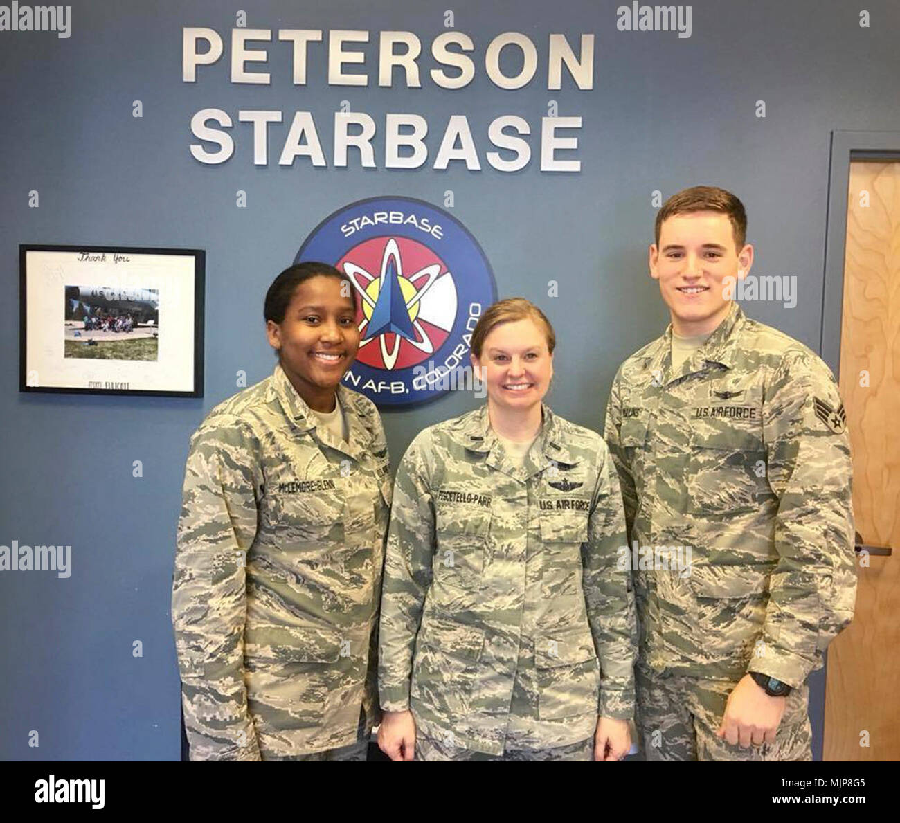 First Lieutenant Cherron McLemore-Glenn, left, 1st. Lt. Justine Pescetello-Parr, center and Senior Airman Kameron Mullins, right, staff instructors with the 50th Operations Support Squadron, gather for a photo after helping teach GPS and other space-related information to students during StarBase Academy at Peterson Air Force Base, Colorado, Feb. 27, 2018. They volunteered to ignite students’ passion for science, technology, engineering and math. Armed Forces and civilians displaying courage bravery dedication commitment and sacrifice Stock Photo