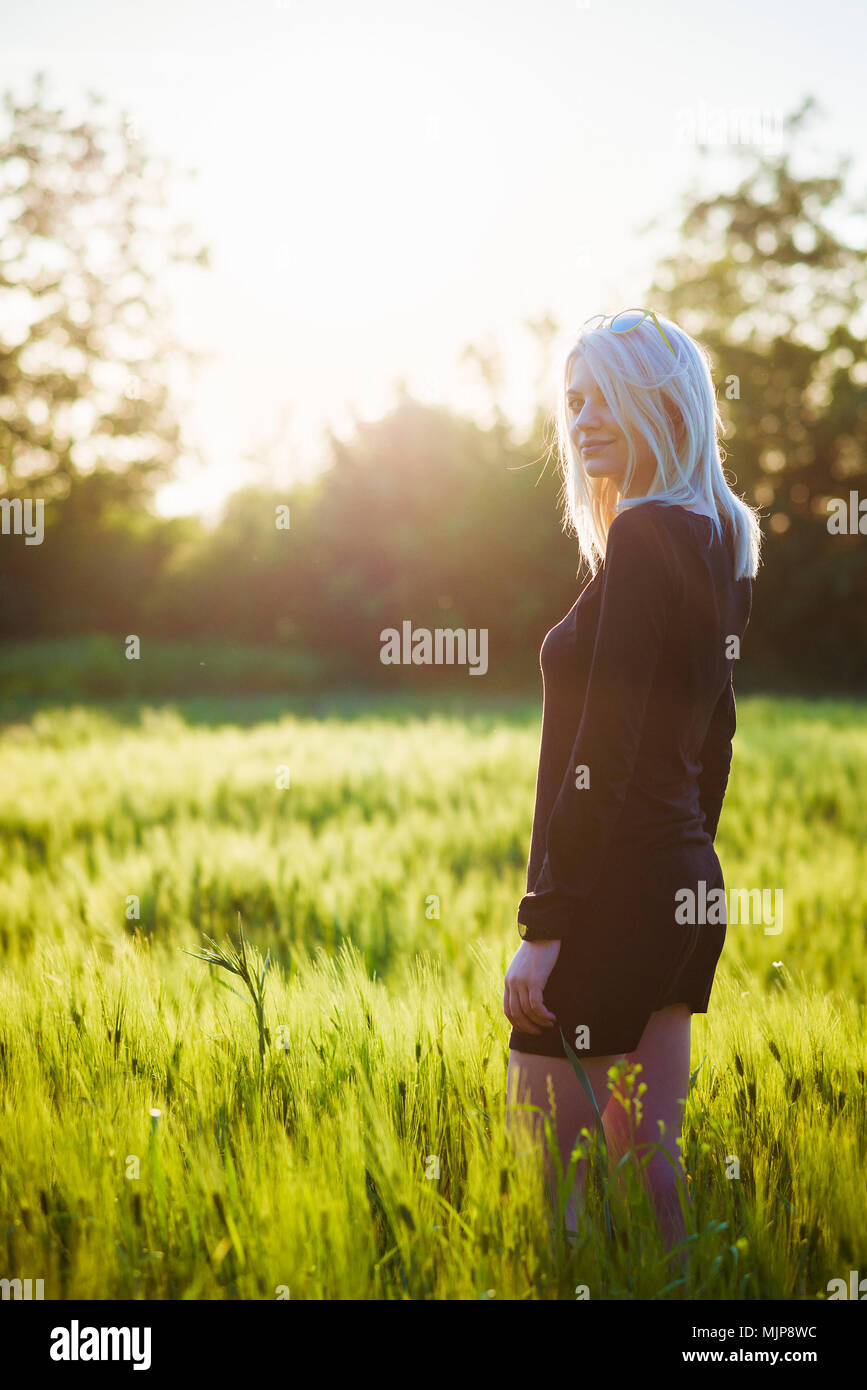 Beautiful young woman standing in wheat field Stock Photo