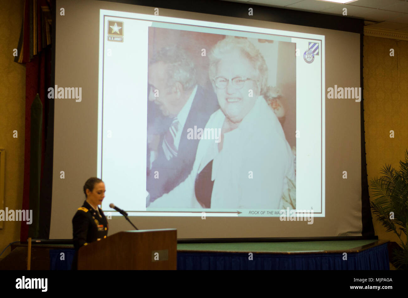 Maj. Alicia L. Pruitt, deputy human resources officer of the 3rd Infantry Division and guest speaker of a Women’s History Month observance ceremony talks about her great-grandmother as a photo of her is displayed at Club Stewart in Fort Stewart, Georgia, March 21, 2018. Pruitt attributes her success and accomplishments to her great-grandmother, Laurette Durand – someone who Pruitt says is her number one female role model. Armed Forces and civilians displaying courage bravery dedication commitment and sacrifice Stock Photo