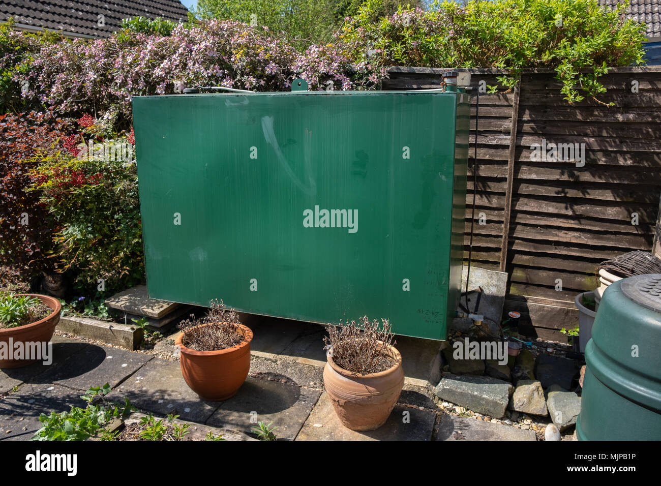 domestic heating oil tank next to a wooden fence in a garden Stock