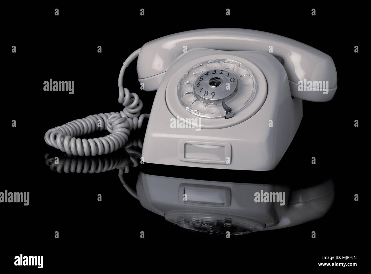 Gray old Swedish 1960s telephone on hook with dial on black background. Stock Photo