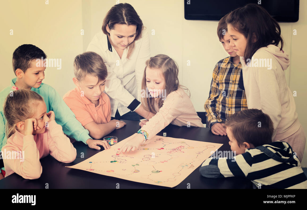 Elementary age calm children sitting at table with board game and dice Stock Photo