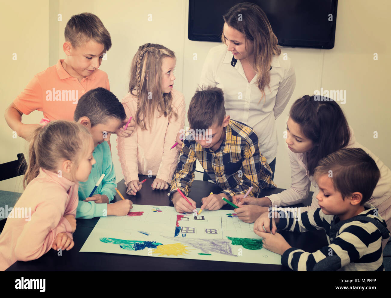 Professor and elementary age children drawing and studying together ...