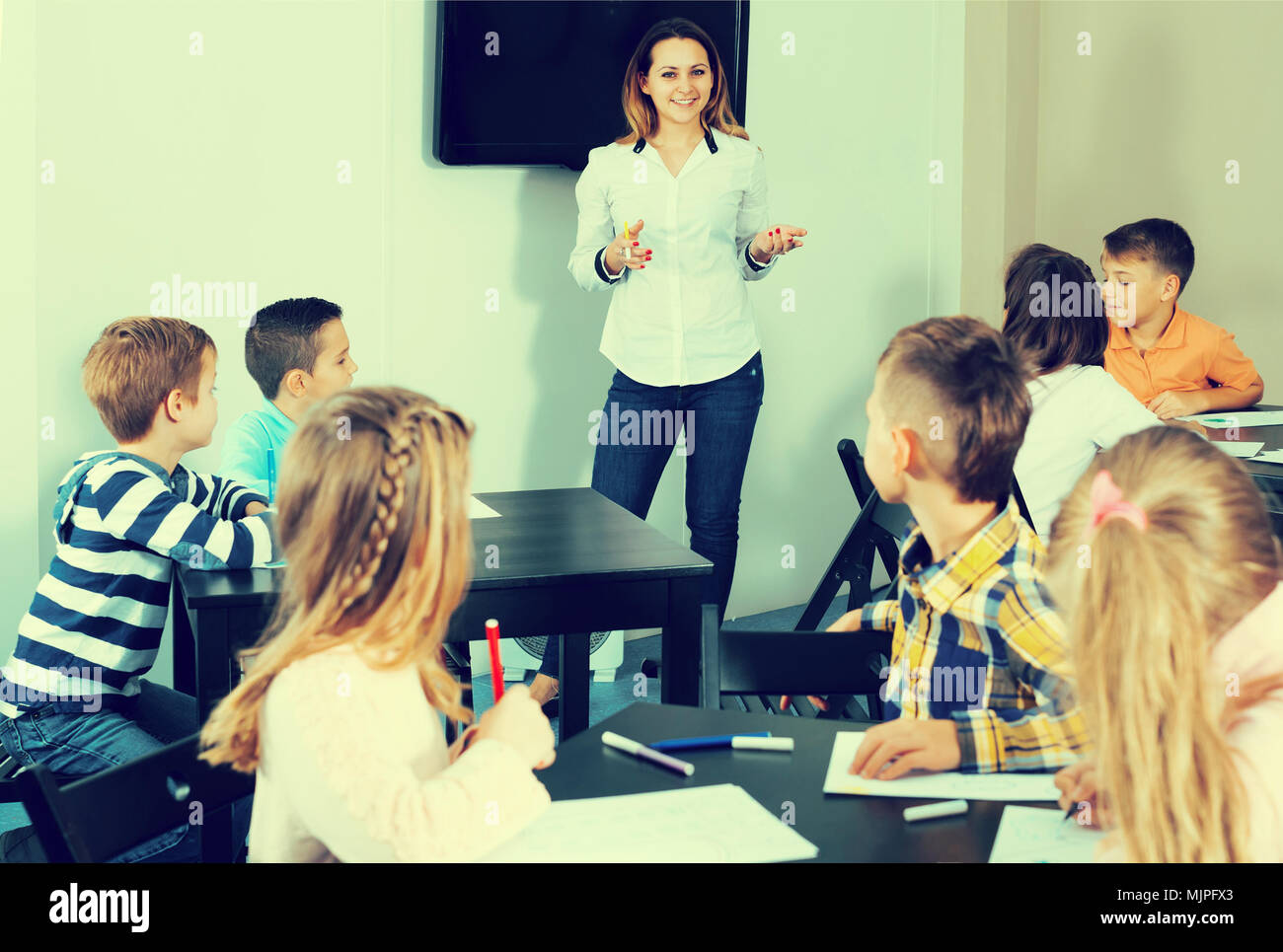 Happy teacher and elementary age children drawing at classroom Stock ...