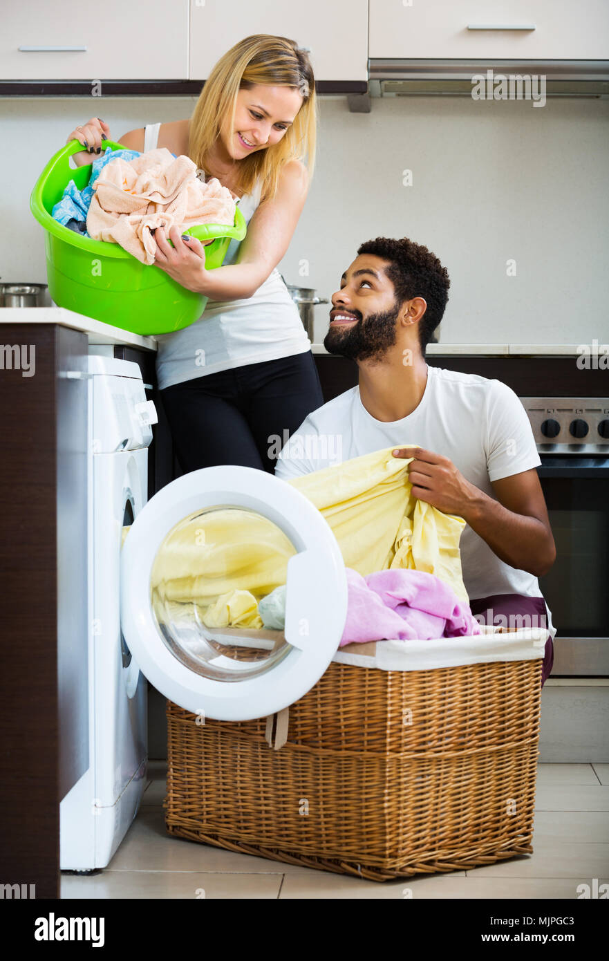 Happy young mixed spouses doing regular laundry and smiling Stock Photo
